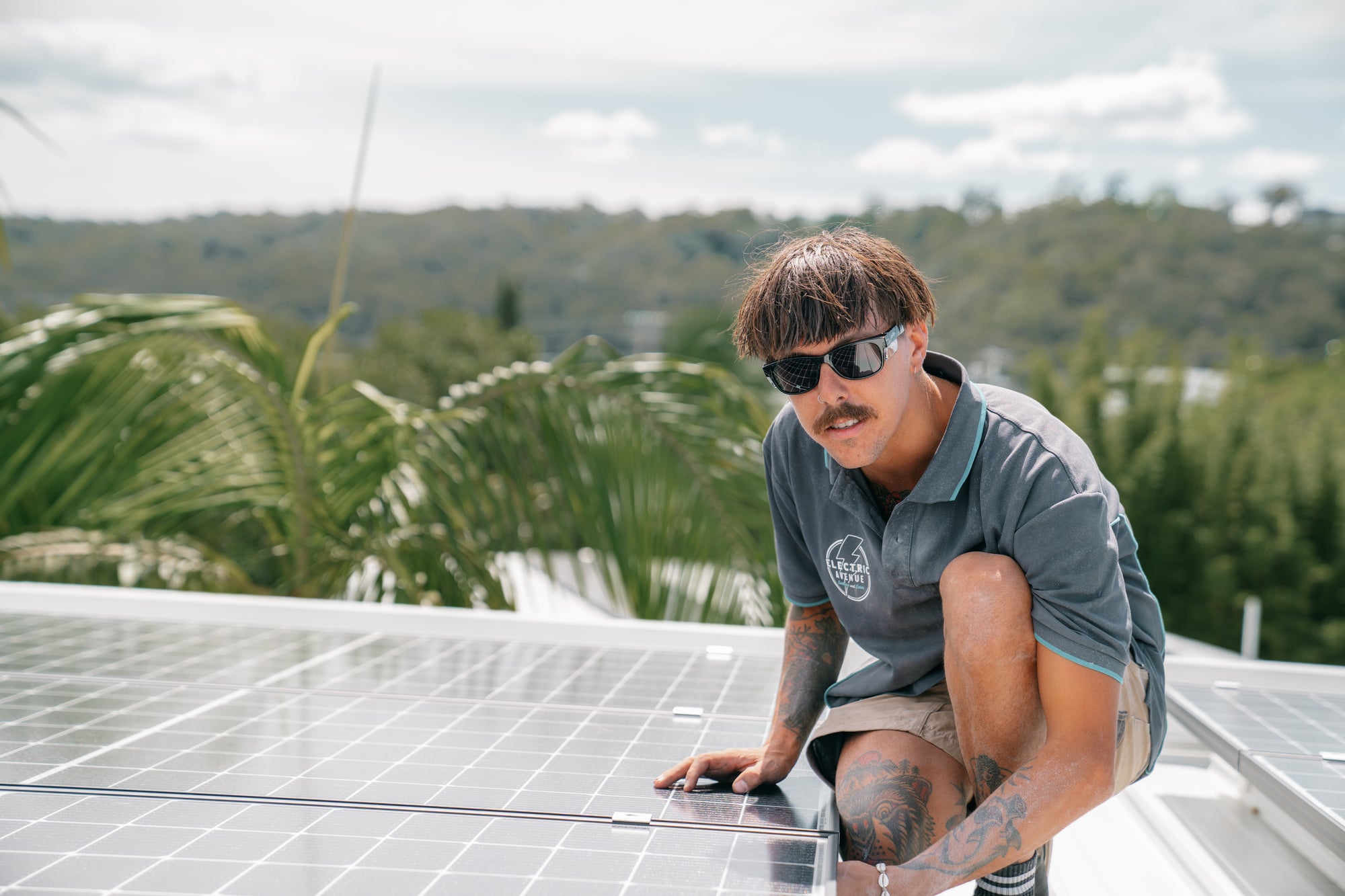 Person installing solar panels on a roof with greenery in the background wearing safestyles - PPE CLUB